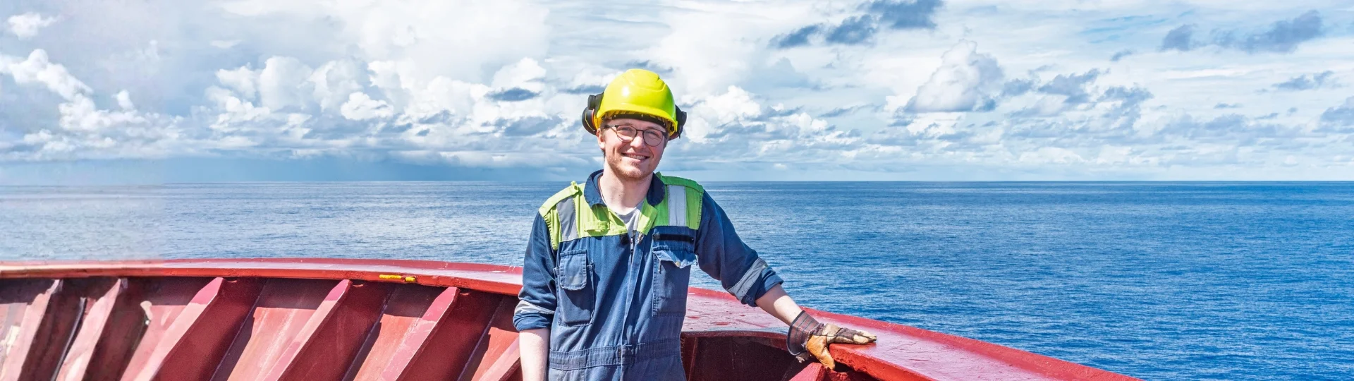 Arbeiter mit Schutzhelm und Arbeitskleidung auf einem Schiff vor dem Meer, symbolisiert vielfältige Jobs beim Lighthaus Marine